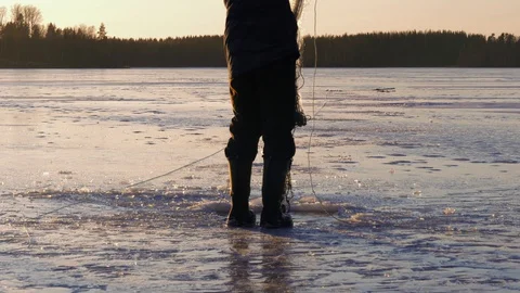 Man setting winter fishing nets at frozen lake Stock Footage 128755409