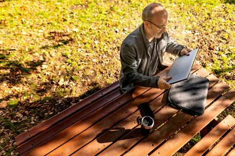Man setting up to work on picnic table in park Stock Photos