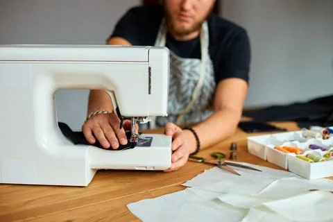 Man sews clothes on sewing machine,  male tailor working with sewing in ateli Stock Photos