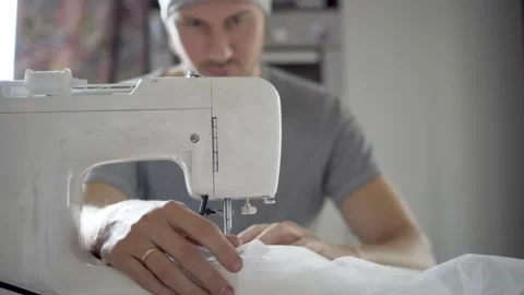 Man sews at a sewing machine. Designer sitting and sewing. Dressmaker working on Stock Footage 163271290