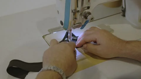 Man sews at a sewing machine. Designer sitting and sewing. Dressmaker working on Stock Footage 254485069