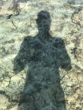 Man Shadow under water on sand shore Stock Photos