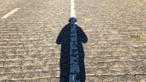 Man shadow is walking at the center of pavement road line Stock Footage 98146526