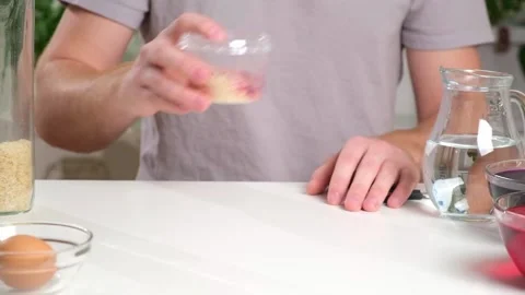 A man shakes container of rice evenly color rice. An unusual way coloring and Stock Footage 236660124