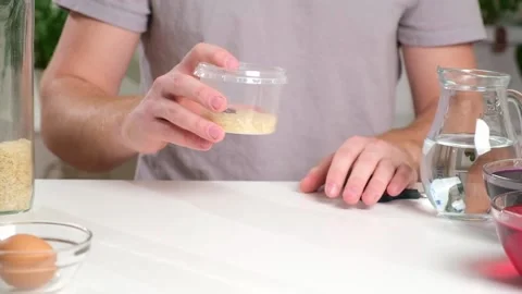 A man shakes container of rice evenly color rice. An unusual way coloring and Stock Footage 236921433