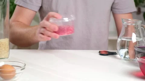 A man shakes container of rice evenly color rice. An unusual way coloring and Stock Footage 237858569