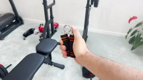 A man shakes an expander with his hand while in the gym Stock Footage 280498372