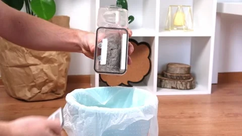 A man shakes out garbage container from a robot vacuum cleaner of wool, dust Stock Footage 198279135