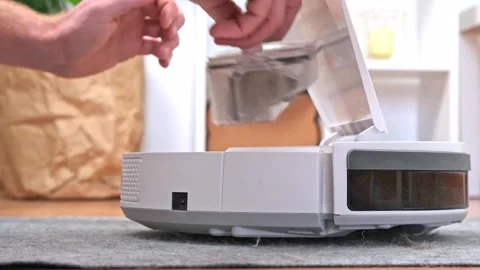 A man shakes out garbage container from a robot vacuum cleaner of wool, dust Stock Footage 199313359