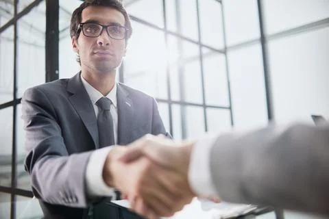 Man shaking hands with partner over office desk Stock Photos