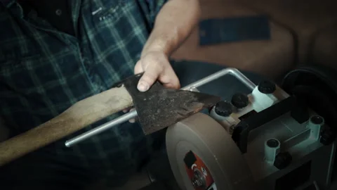 Man sharpening axe on a grinder. Hand close up Stock Footage 143672998