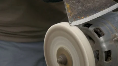 A man is sharpening a big ax on a makeshift machine. Video stock 77866180