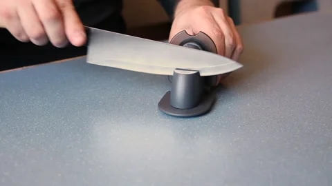A man is sharpening a chef's knife on a knife stand. Stock Footage 152770413