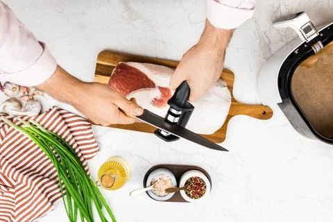 Man sharpening a kitchen knife with a manual sharpener tool for meat. Raw p.. Stock Photos
