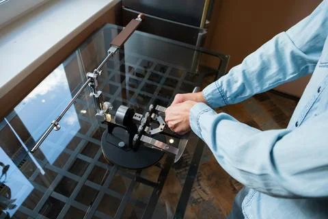 Man sharpening kitchen knife on professional manual machine. Metal blade 스톡 사진