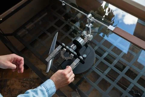 Man sharpening kitchen knife with professional manual sharpening system 写真素材