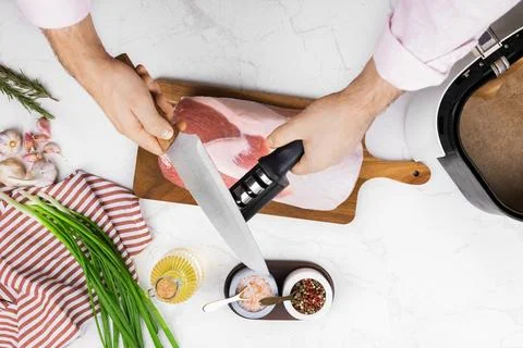 Man sharpening a kitchen knife with a sharpener to prepare raw meat. Male h.. Stock Photos