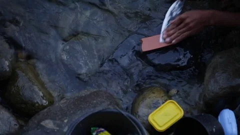 Man sharpening knife in a river in Indonesia Stock Footage 71830048