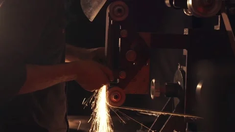 Man sharpening knife with sparks. Work on a sharpening machine. Stock Footage 134792132
