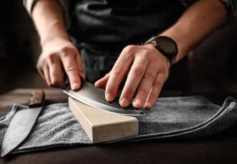 Man sharpening a knife with whetstone Stock Photos