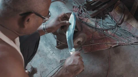 Man sharpening a large metal knife on a machine Stock Footage 142745394