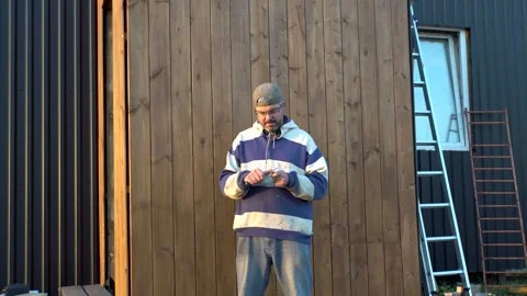 Man sharpening pencil against wall of house 4K Video stock 294827008