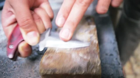Man sharpening push dagger on a whetstone Stock Footage 276409583