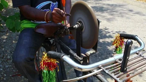 A man sharpening a scissor on a rotating whetstone 60 FPS FHD Stock Footage 130793362