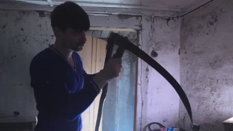 Man sharpening a scythe in the old building. Medium shot Video stock 136852463
