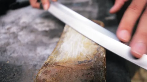 A man sharpening short katana on whetstone Stock Footage 276409554