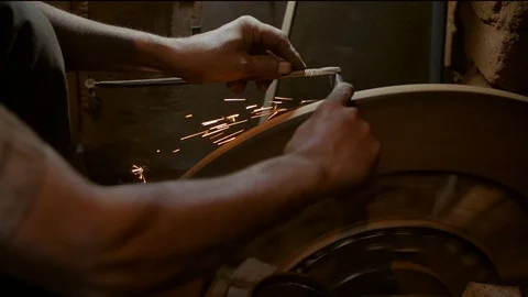 A man sharpening a tool in his hand using a blade sharpening machine Stock Footage 112773131