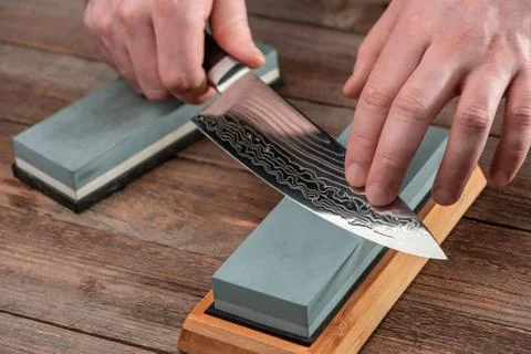 Man sharpens a Gyuto knife using a whetstone Stock Photos