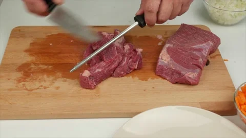 A man sharpens a kitchen knife on knife sharpener and cuts meat,close-up Stock Footage 133715091