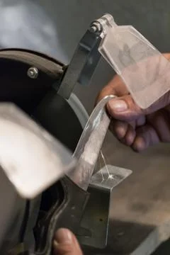 Man sharpens a knife on an electric grindstone Stock Photos