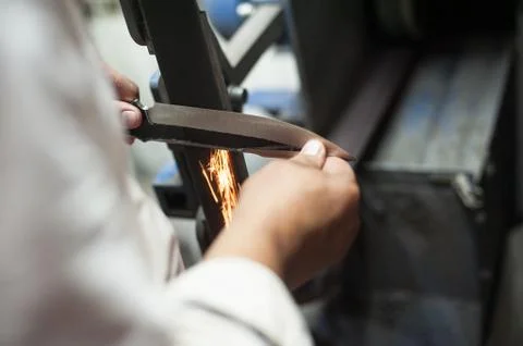 A man sharpens a knife on the machine sparks fly Stock Photos
