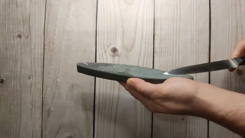 A man sharpens a knife with Soviet emery Stock Footage 220884080