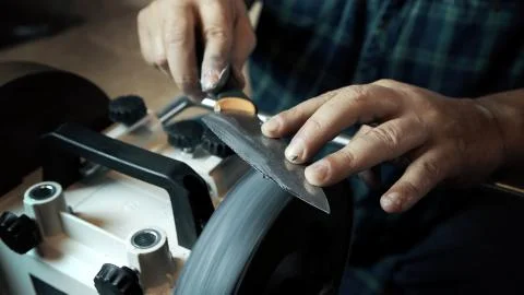 Man sharpens knives on a grinder. Close up hand Stock Photos