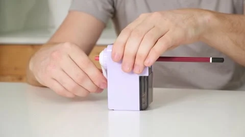 A man sharpens a pencil on desktop rotating pencil sharpener. Stock Footage 242298749