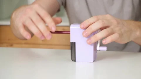 A man sharpens a pencil on desktop rotating pencil sharpener. Stock Footage 243288896