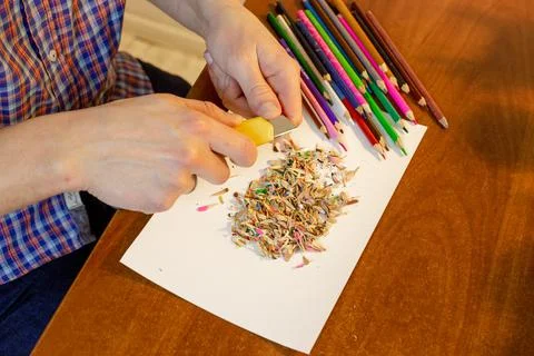 A man sharpens a pencil with a stationery knife Stock Photos