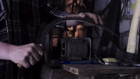 A man sharpens a sickle on a grinder sharpener close-up Stock Footage 136442784