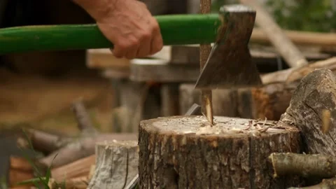A man sharpens a thin stake and cuts chop wood for the garden and stove Stock Footage 138405230