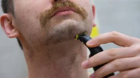 The man shaves his big beard. The guy shaves off his big beard. Young guy shaves Stock Footage 232632845