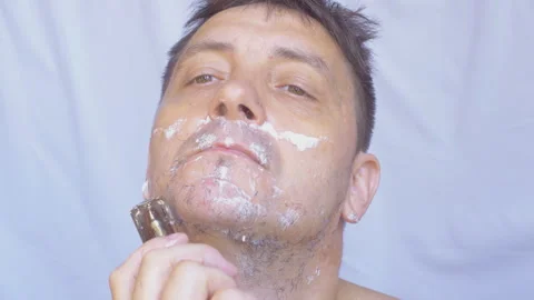 A man shaves with a razor. Stockbeeldmateriaal 338398192