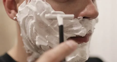 Man is shaving with foam using disposable razor in bathroom, closeup, side view. Stock Footage 137438089
