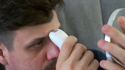 Man shaving hair on face between eyebrows using electric epilator plucking hair. Video stock 152829294