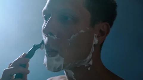 Man shaving his face with razor in steamy bathroom after shower, close-up with Stock Footage 312329064