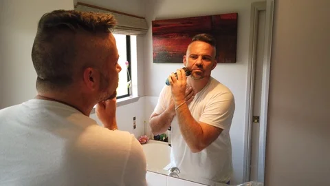 Man shaving in the mirror puts on the final touches wiping his face to see Stock Footage 121870052
