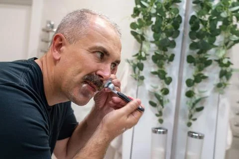Man shaving with razor using foam in bathroom in the morning Stock Photos