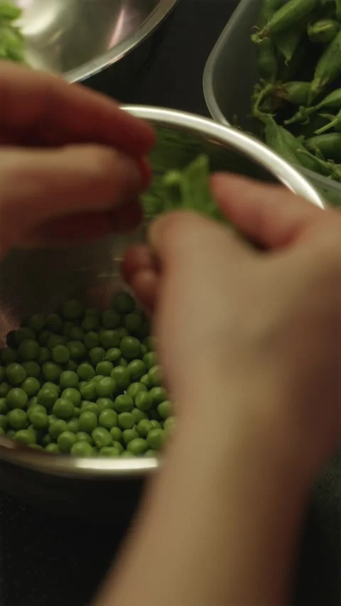 Man shelling raw green peas from pods at home Stock Footage 338395312